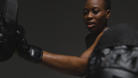 Close-Up-Studio-Shot-Of-Woman-Wearing-Boxing-Gloves-Sparring-With-Trainer